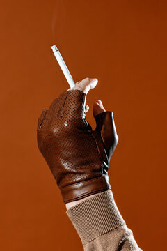 a close-up of a gloved hand holding a cigarette