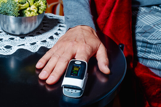 a man checking oxygen saturation with a pulse oximeter at home