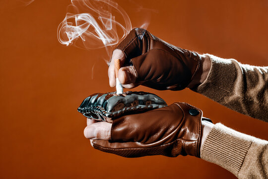 a side view of a man putting out a cigarette in an ashtray