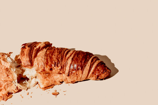 a split croissant with crumbs on a beige surface