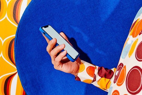 man holding a blank smartphone over a circular blue fabric
