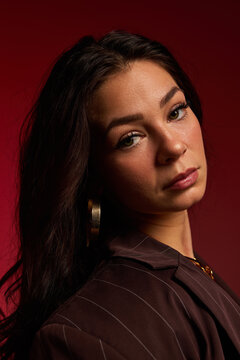 Woman with long hair poses against a red background in studio