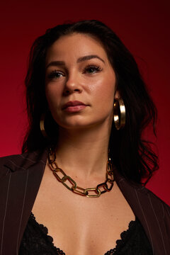 Woman wearing jewelry poses in front of red background