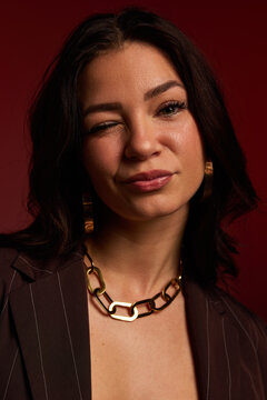 Woman winks while posing against a red background in casual atti
