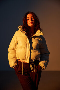 Woman wears winter jacket and poses in warm light