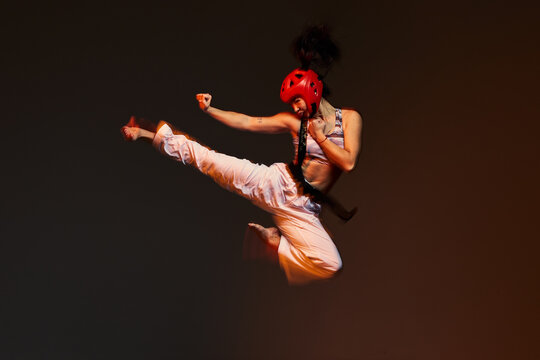 Martial artist performs high kick during training session indoor