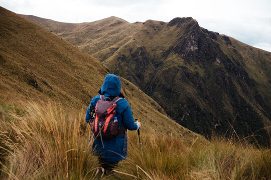 Hiker walking on grassy trail toward mountains