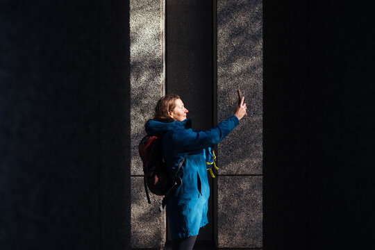 Woman taking selfie outdoors between tall stone columns
