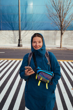 Portrait of woman holding phone on striped crosswalk