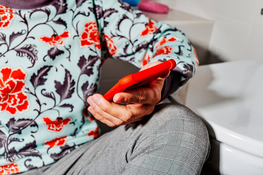 a close-up of a man using his smartphone with a red case