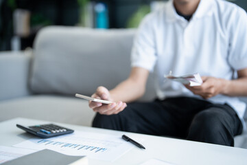 Man calculate finances home pay bills taxes on mobile phone financial at home