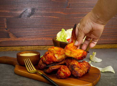 Food: Grilled marinated chicken wings on a wooden cutting board, black background