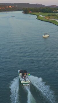 Aerial view of motorboat cruising on Lake Travis Texas at sunrise with scenic Hill Country landscape - Vertical Aerial