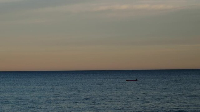 A canoeist and a diver in the sea at sunset. Slow motion x0.5.