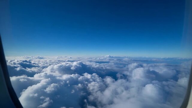 Aerial view of fluffy white clouds and blue sky through airplane window during flight
