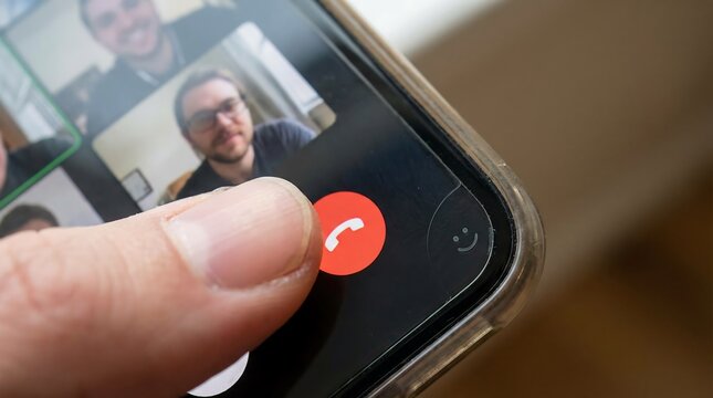 Close-up of a finger pressing the red end call button on a smartphone during a video call.