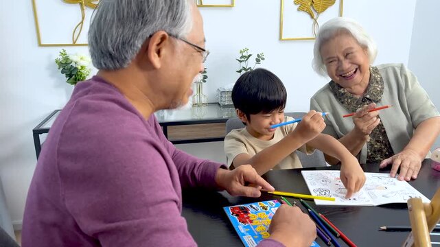 Asian Grandparents and Child Coloring Together at Home Table