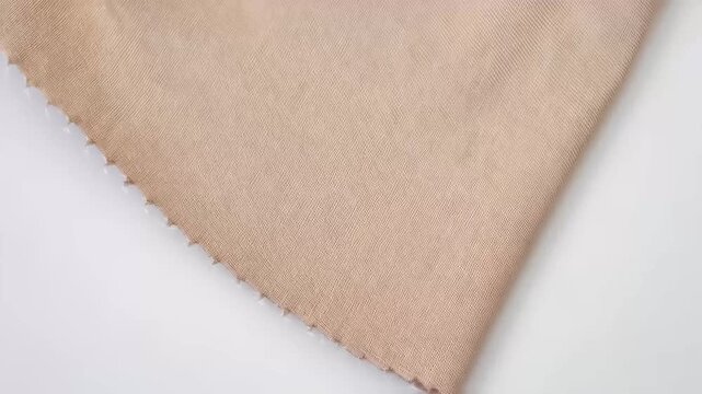 Beige textile with textured surface and serged edge against white background