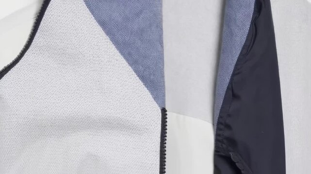 Close-up of a jacket with a zipper, textured fabrics, and color blocking