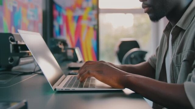 Man working on laptop at desk in modern office with colorful background