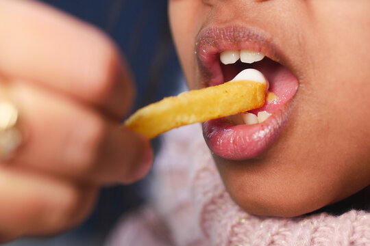 Child eats French fry during snack time at home