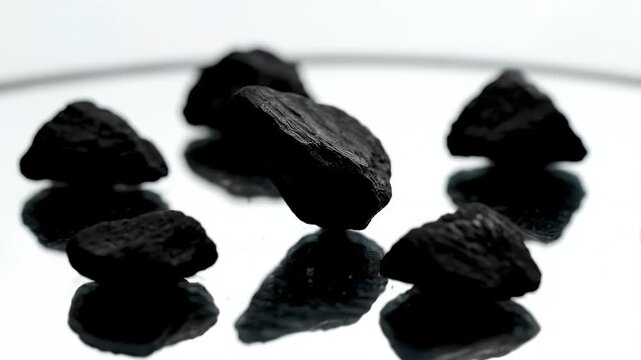 Industrial Black Coal Lumps Reflecting on Clean White Surface