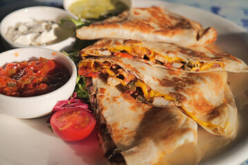 Delicious quesadilla served with salsa and sour cream