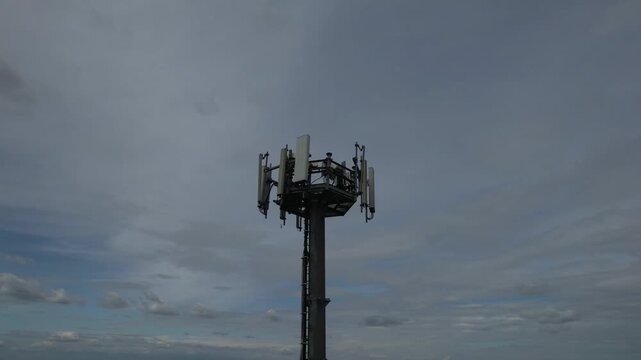5G cellular base station tower showing multiple sector panel antennas, remote radio units, mounting brackets, and cabling, illustrating modern mobile network infrastructure, slow motion shot