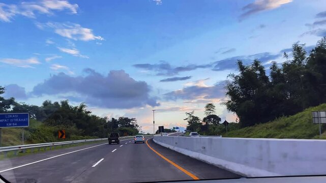 Scenic highway at dusk with dramatic clouds and soft evening light, capturing a peaceful road trip atmosphere and open journey through a lush tropical landscape.