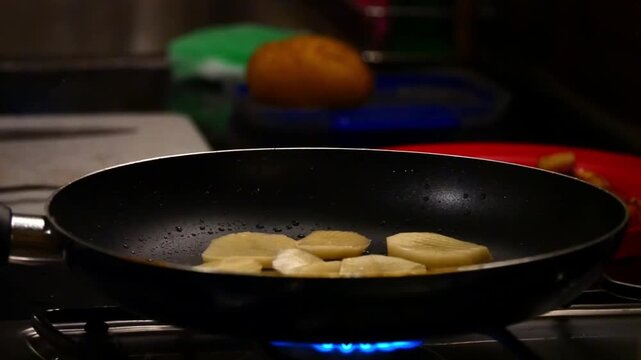 Pommes de terre en tranches cuisant dans une po&ecirc;le &ndash; ambiance sombre