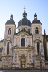 Fototapeta premium Baroque style church facade with domes and towers under clear blue sky in France