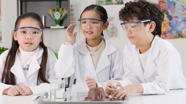 Asian Students in Lab Coats Perform Baking Soda and Vinegar Volcano Experiment