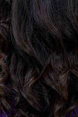 Closeup dark curly hair with glitter, stylistapplied shimmer on glossy tresses, intimate texture detail, evening beauty mood, studio lighting enhancing depth and shine