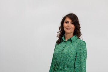 Confident woman wearing textured green dress with inviting smile, Professional lifestyle image capturing woman in bright patterned clothing with approachable demeanor