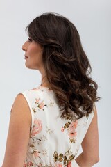 Serene female figure with floral attire and reflective mood, Graceful female profile dressed in flowers against soft studio background for versatile promotional purposes