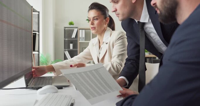 Colleagues and managers conduct business analysis strategy. Working at a large monitor, they compare reports and refine plans for upcoming projects. Clear concept of data driven teamwork.