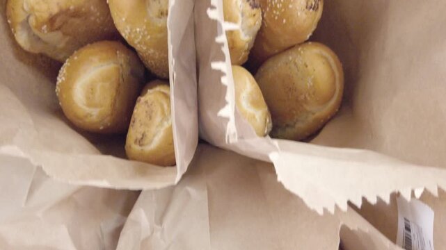 Zenithal view of fresh bread loaves packed inside paper bags at bakery.