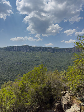 Breathtaking panoramic view of the rolling green hills and deep valleys of Sardinia under a bright blue sky with soft white clouds.
