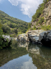 Fototapeta premium Scenic view of the transparent natural pools and rocky riverbed of Sa Stidiosa, surrounded by green Mediterranean hills in Sardinia, Italy.