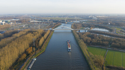 Cargo ship navigating amsterdam rhine canal with bridge and infrastructure