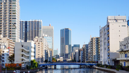 Fototapeta premium 青空の下に立ち並ぶ都会的な高層ビルと運河の風景