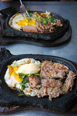 close up of vietnamese sizzling steak or bo ne served on a hot cow shaped cast iron plate with sunny side up egg pate and butter for a traditional street food breakfast
