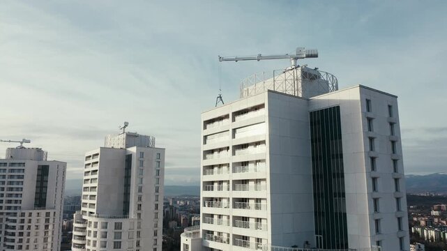 Construction crane lifting materials on skyscraper roof