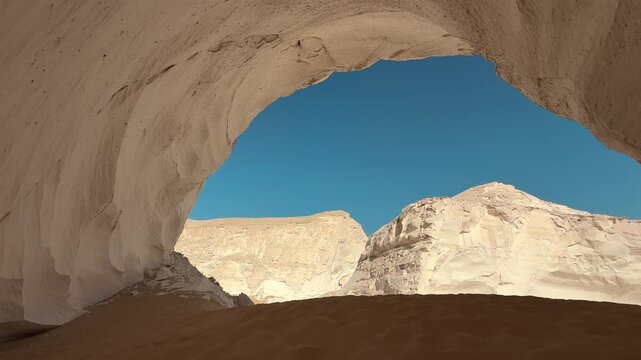 Panoramic view from natural arch in white limestone rock and sand dunes in Sahara Desert. Moon Cave in White Desert National Park