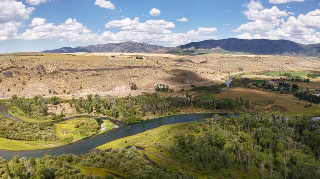 Drone shot gliding over patchwork farmland fields and irrigation ditches at sunrise, with long shadows and a bright sun shining over the landscape