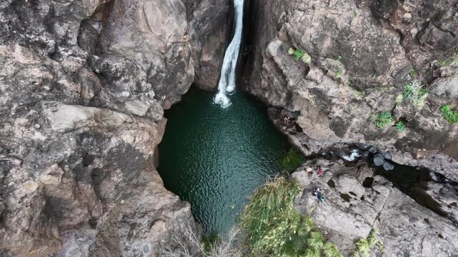 Charco Azul, Agaete, Gran Canaria: Aerial view of a waterfall plunging into a natural pool inside a rocky ravine in Spain