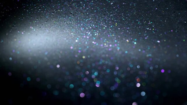Shimmering multicolored glitter particles on a dark textured surface