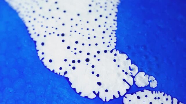 Vibrant blue ink bleeding into white fluid with jagged dark borders