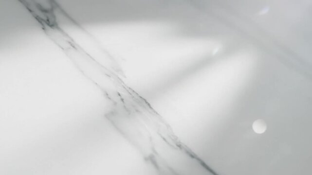 Close up view of white marble countertop with grey veining and reflections of light