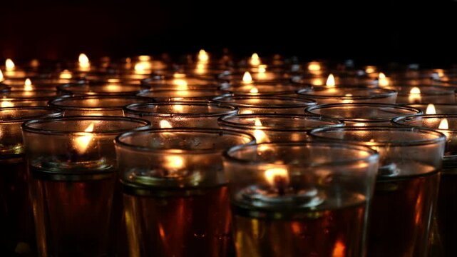 Rows of glowing tea lights in glass holders create a warm, serene ambiance in the darkness